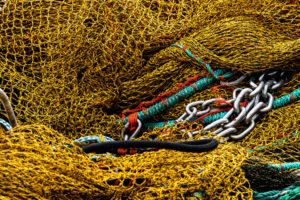 Grundschleppnetzfischerei-Moratorium: Nahaufnahme eines gelben Fischernetzes. Seile und Stahletten liegen darüber