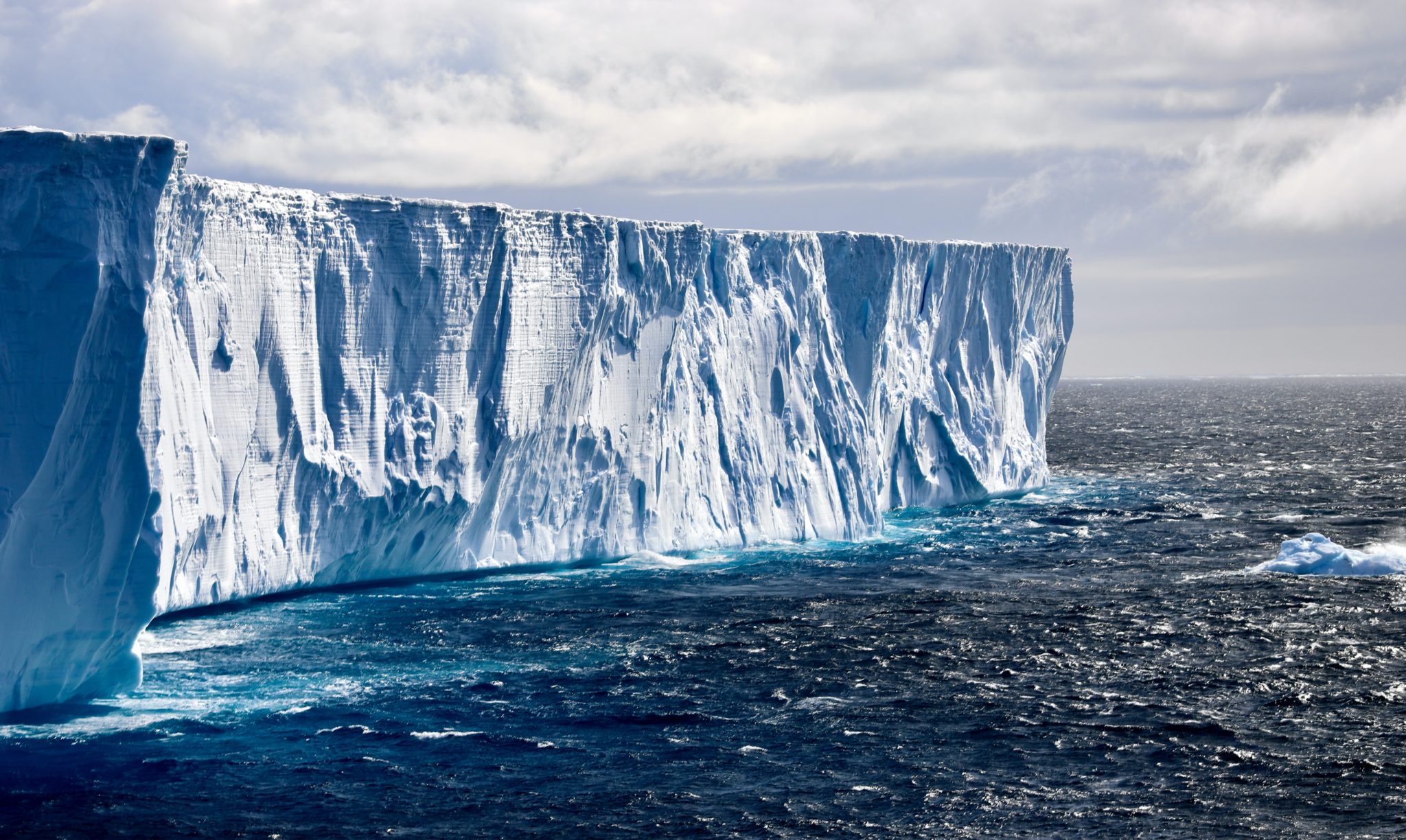 Weddell-Meer, ein gewaltiger Eisberg ragt aus dem Meer. Am Himmel bilden sich dicke Wolken