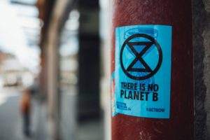 An einem Laternenpfahl klebt ein Sticker von Extinction Rebellion mit der Aufschrift " There is no planet B"