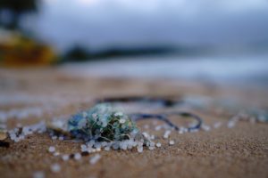 Mikroplastik-Kügelchen im Netz am Strand und auf dem Sand