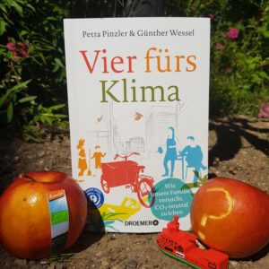 Das Buch Vier fürs Klima vor einem Fahrrad mit einem Bioapfel und einem konventionellen Apfel