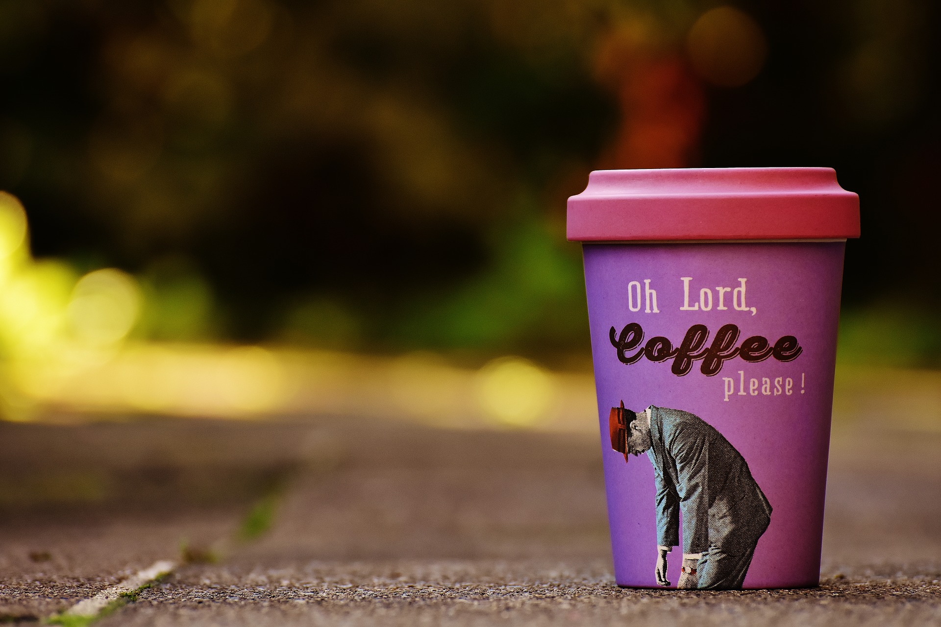 Auf dem Boden steht ein pink-lilaner Coffee-to-go Bambusbecher mit der Aufschrift "Oh Lord, Cofee please"