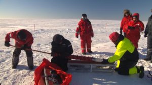 Das Bild zeigt sieben Wissenschaftler auf der zugefrorenen Ostsee. Alle tragen Schneeanzüge und entnehmen Eis aus dem Untergrund.