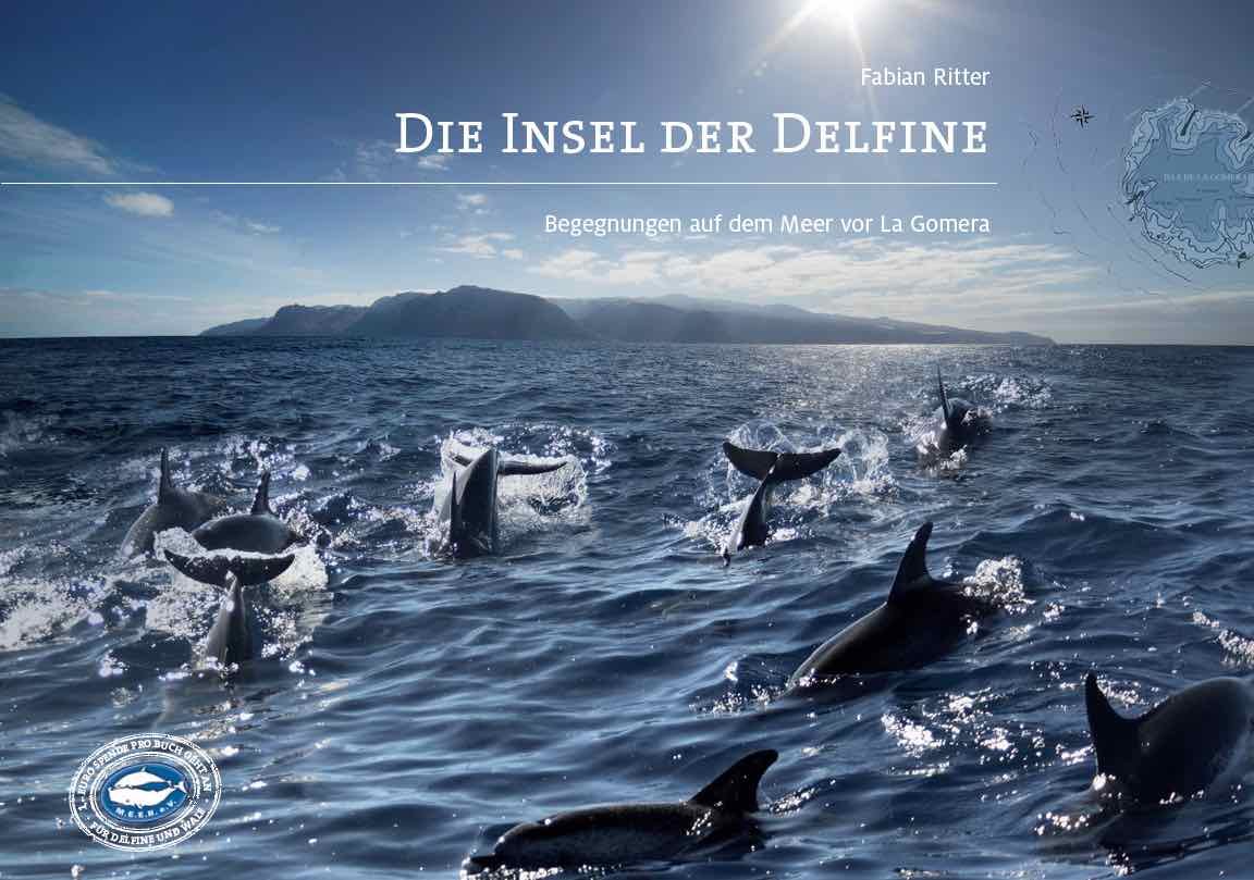 Das Cover des Buches. Eine Delfinschule schwimmt vor La Gomera und springt aus dem Wasser. Das Meer ist von knapp über der Wasseroberfläche fotografiert. Im Hintergrund sieht man die Berge der Insel. Titel: Die Insel der Delfine- Begegnungen auf dem Meer von La Gomera
