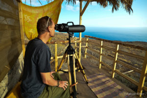 Der Autor Fabian Ritter sitzt auf der Aussichtsplattform auf La Gomera. Er blickt durch ein großes Teleskop. Im Hintergrund sieht man das endlose Meer, auf das das Teleskop gerichtet ist