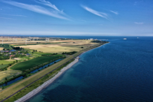Luftaufnahme von der Küste Fehmarns, mit blauem Wasser und blauem Himmel.