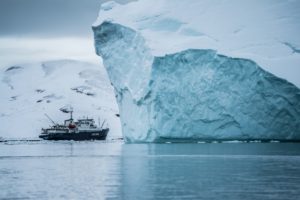 Ein Forschungsschiff schwimmt zwischen zwei riesigen Eisbergen in der Arktis.