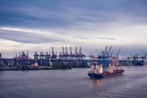 Ein kleines Schiff fährt vor dem Hamburger Hafen auf der Elbe entlang