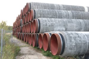 Mehrere Rohre für den Bau von Nord Stream 2 liegen gestapelt auf der Erde