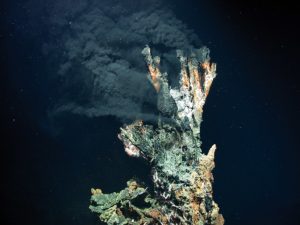 Ein Schwarzer Raucher als Teil von einem Hydrothermalfeld bläst schwarzen Rauch in das dunkle Wasser