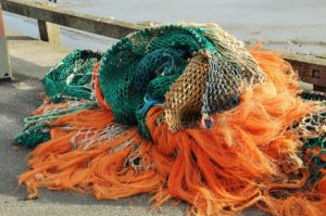 Fischereimaßnahmen: Mehrere bunte Fischereinetze liegen am Steg übereinander