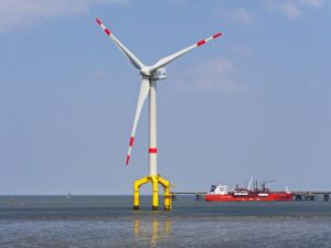 Ein Windrad für Offshore-Windenergie steht neben einem Schiff im Wattenmeer