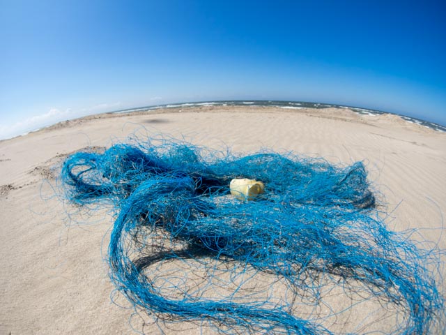 Ein blaues Geisternetz liegt verlassen am Strand