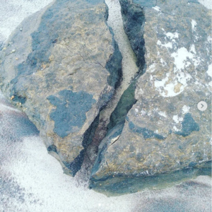 Ein gebrochener Stein liegt auf Sand
