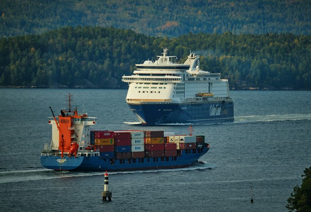 Fähre und Containerschiff auf dem Meer mit Wald im Hintergrund